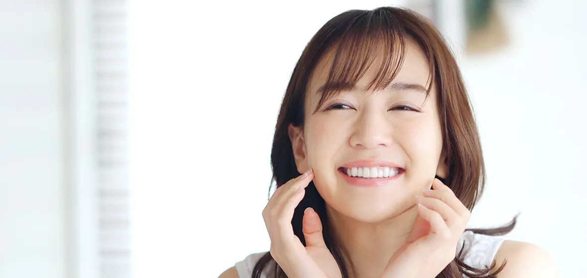 白い歯を見せてほほえむ女性（イメージ）